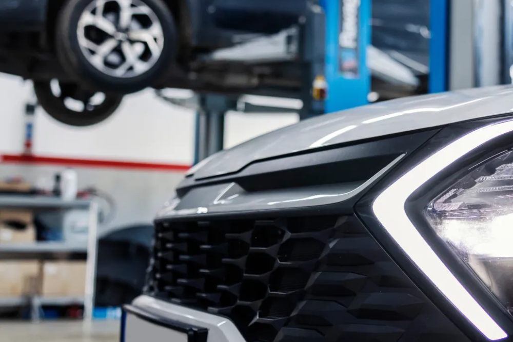 Car Maintenance in Ipswich, MA At New Meadows Motor Car. Front grille and headlight of a modern SUV parked inside an auto repair shop bay