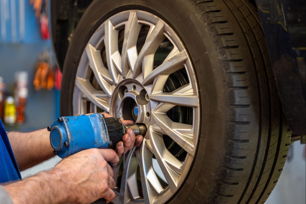 Tire Inspection in Ipswich, MA at New Meadows Motor Car. Mechanic using an impact wrench to service a tire rim during a tire inspection.